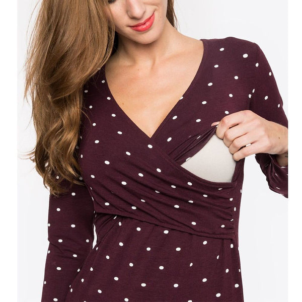 Woman wearing a burgundy top with white polka dots holding a clutch against a white background