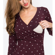 Woman wearing a burgundy dress with white polka dots holding a clutch against a white background