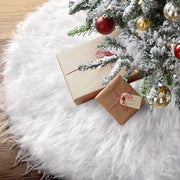 Two wrapped gifts under a decorated Christmas tree on a white fur rug.