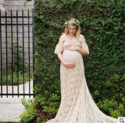 Pregnant woman in a flowing dress standing outdoors with greenery in the background