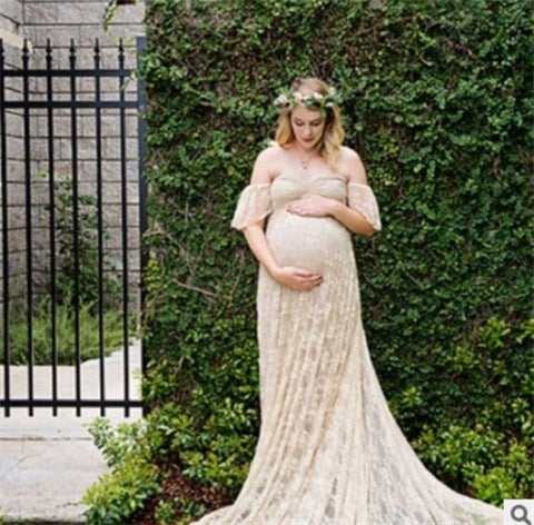Pregnant woman in a flowing dress standing outdoors with greenery in the background