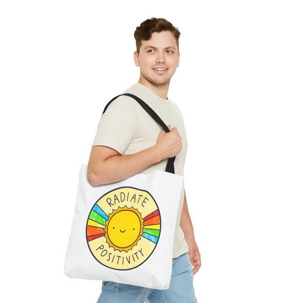 Man holding a tote bag with a sun design and 'Radiate Positivity' text on a white background