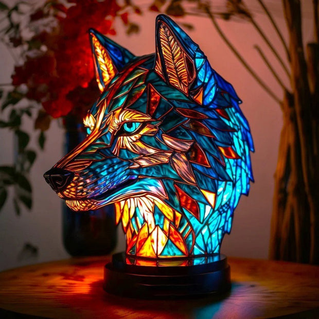 Stained glass wolf head lamp on a wooden surface with flowers in the background