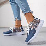 Blue patterned sneakers worn with light blue jeans on a neutral background
