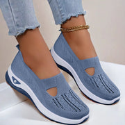 Blue slip-on shoes with white soles worn by a person on a light background