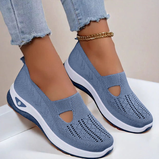 Blue slip-on shoes with white soles worn by a person on a light background
