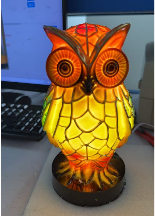 Owl-shaped lamp with stained glass design on a desk.