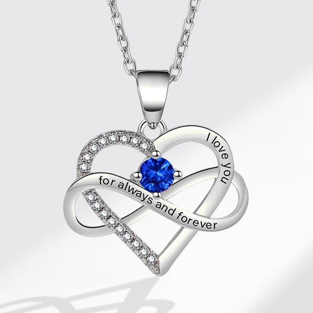 Heart-shaped silver necklace with blue gemstone and 'I love you' engraving on a white background