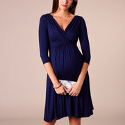 Woman wearing a navy blue dress with a beige background