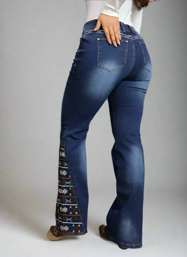 Person wearing blue jeans with decorative side panels against a gray wooden background