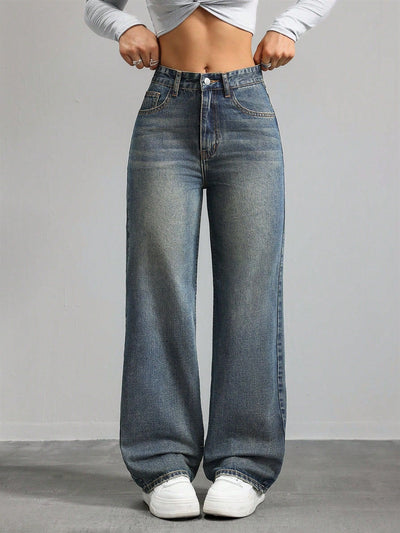 Person wearing high-waisted blue jeans on a plain background