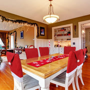 Dining room with Christmas decorations, including red chairs with Santa hats and a table set for a meal.