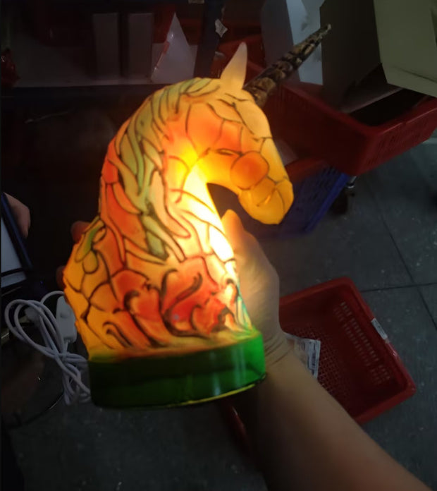 Hand holding a dragon-shaped lamp with colorful design