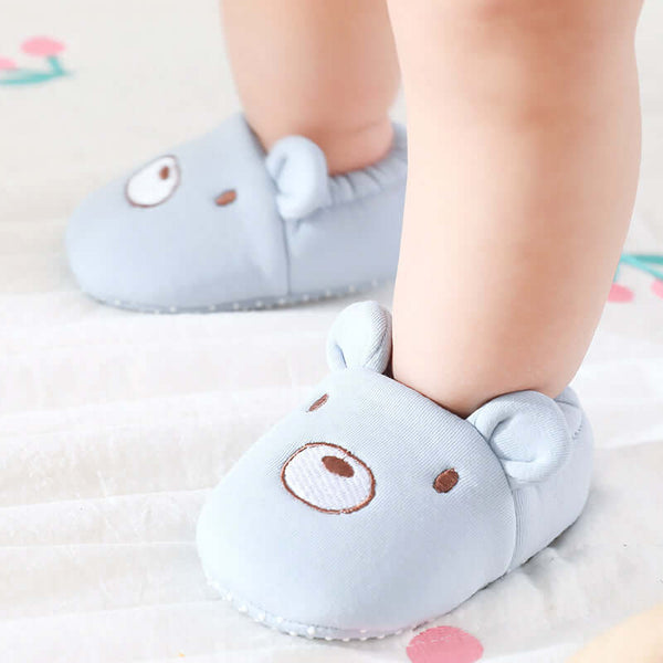 Children's blue slippers with cartoon face design on a light background