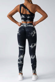 Person wearing black and white tie-dye athletic leggings and sports bra on a light gray background