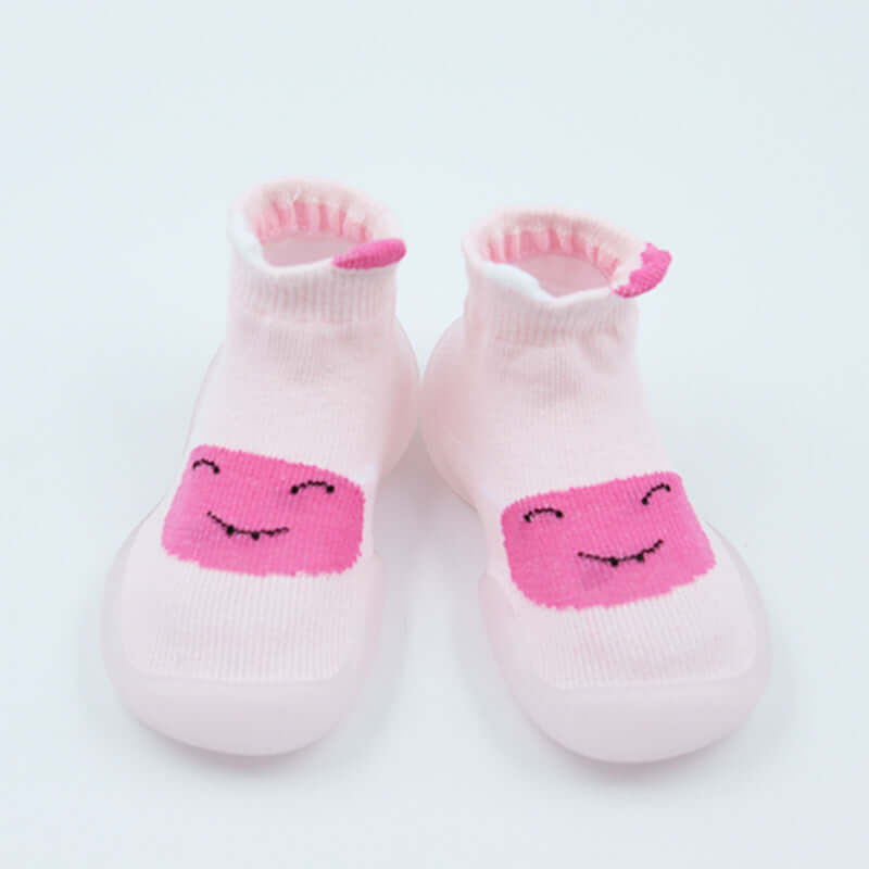 Pair of pink baby socks with smiley face design on a white background