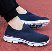 Navy slip-on shoes with white soles worn on a red surface