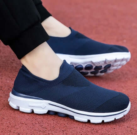 Navy slip-on shoes with white soles worn on a red surface
