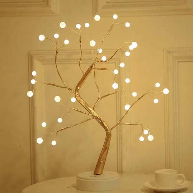 Decorative LED tree with lights on a white surface against a beige wall.