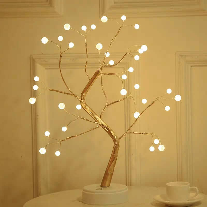 Decorative LED tree with lights on a white surface against a beige wall.