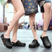 Two pairs of feet wearing black clogs on a blurred city street background.