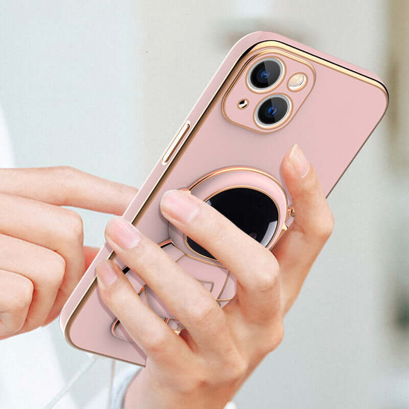 Pink phone case with ring holder held by a hand against a light background