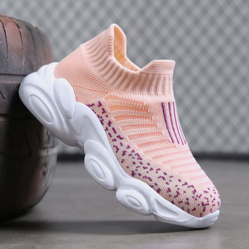 Pink and white sock sneaker on a gray surface with a blurred background