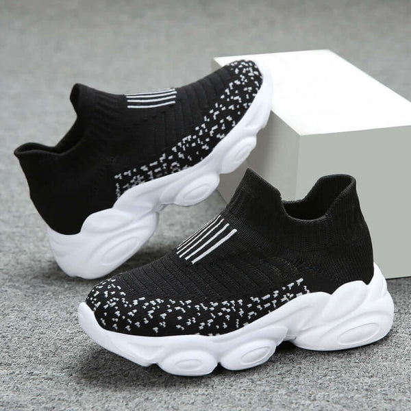 Black and white sock sneakers on a gray surface with a white block background