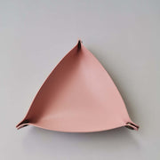 Triangular pink leather wall hook on a light gray background