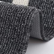 Close-up of a textured black and gray rug corner on a light background