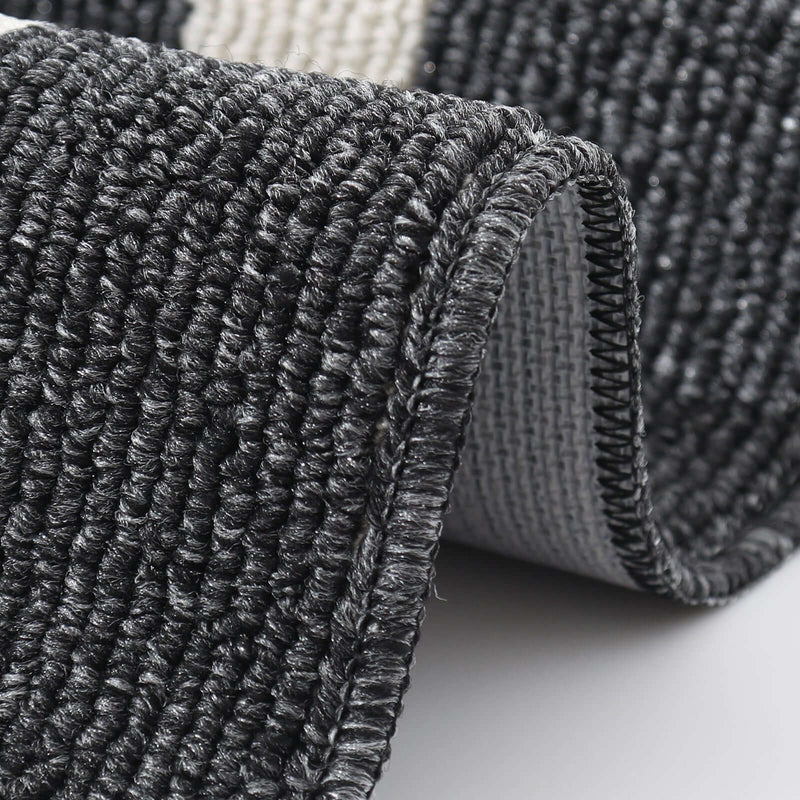 Close-up of a textured black and gray rug corner on a light background