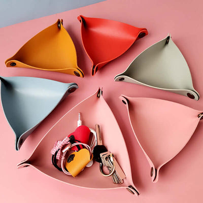 Colorful geometric key holders on a pink background with keys and small items.