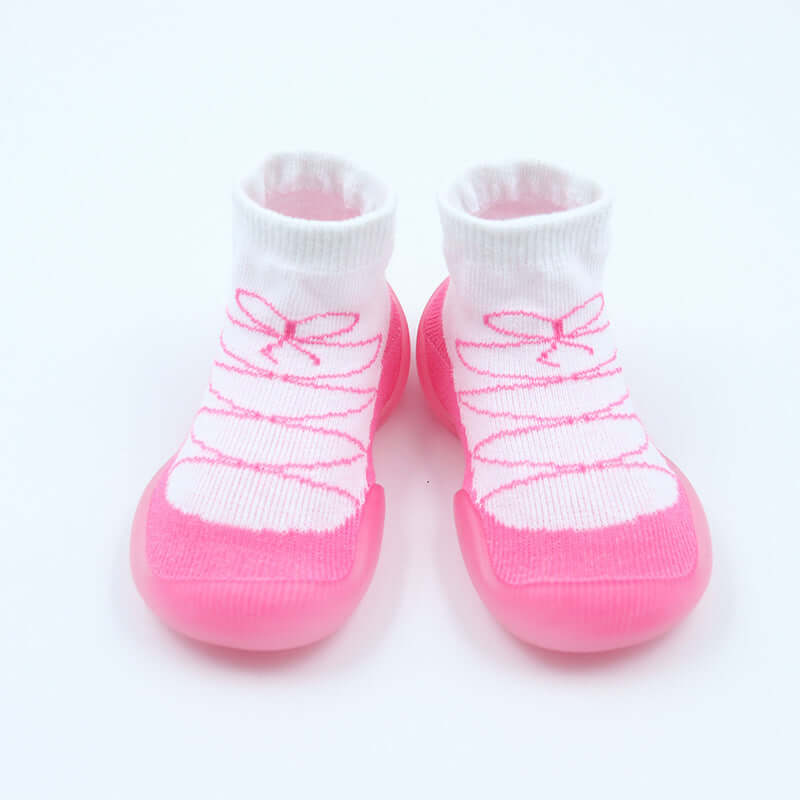 Pair of baby socks with pink soles and white tops on a light pink background