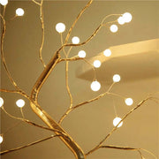 Decorative gold branch with string lights on a beige background