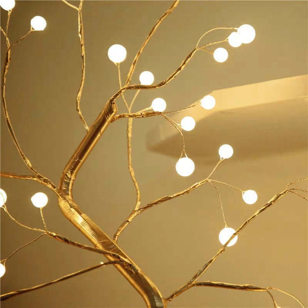 Decorative gold branch with string lights on a beige background