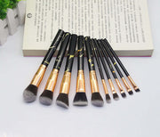 Set of makeup brushes with black and gold handles on a white background