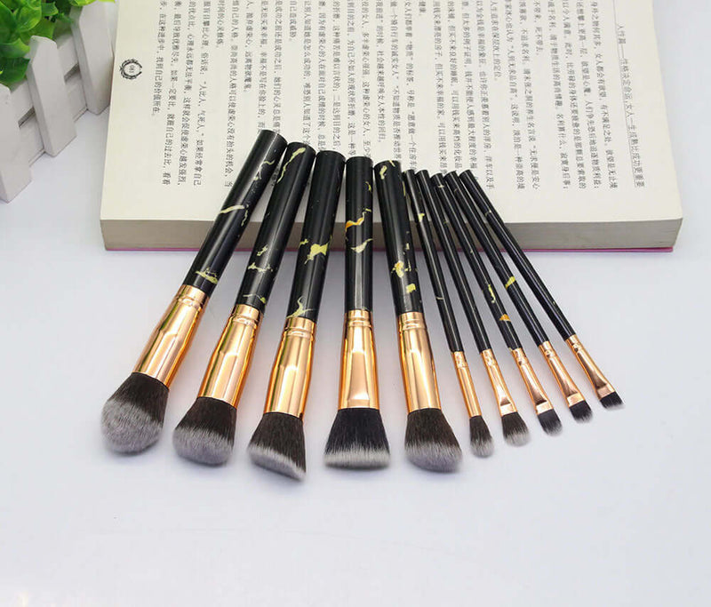 Set of makeup brushes with black and gold handles on a white background