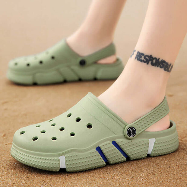 Green clogs on feet with a sand background