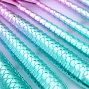 Mermaid scale patterned straws in turquoise, pink, and purple on a white background