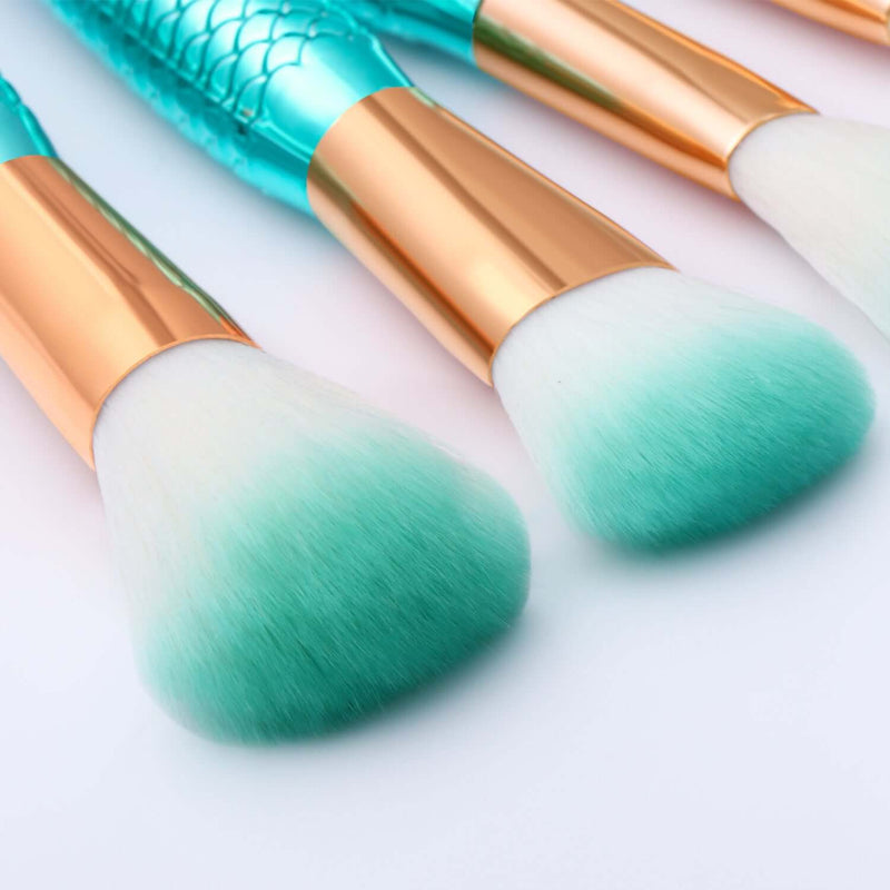 Makeup brushes with gradient green bristles and gold handles on a light background