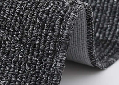 Close-up of a textured black rug on a light gray surface