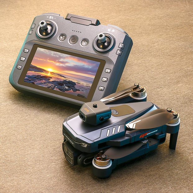 Drone controller with screen displaying a sunset over water, accompanied by a folded drone on a beige surface.