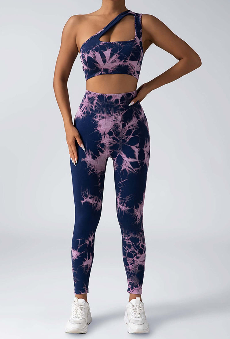 Person wearing a navy and pink tie-dye sports bra and leggings set on a white background