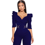 Woman wearing a purple jumpsuit with ruffled sleeves on a white background