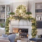 Decorated fireplace with greenery and lights in a living room setting.