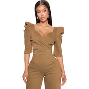 Woman wearing a brown jumpsuit with ruffled sleeves on a white background