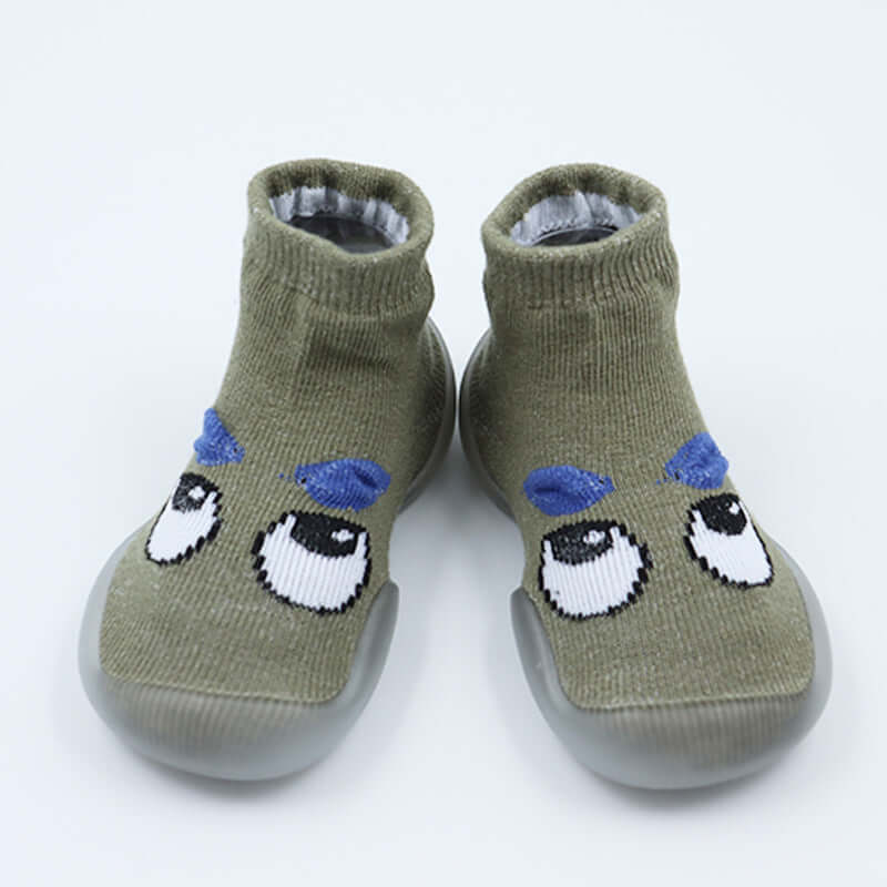 Pair of green baby shoes with cartoon face design on a white background