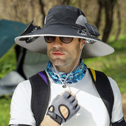 Man wearing a wide-brimmed hat, sunglasses, and a backpack outdoors.