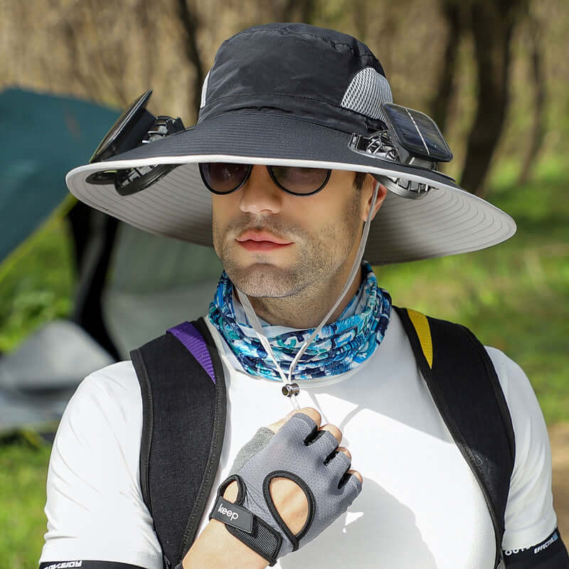 Man wearing a wide-brimmed hat, sunglasses, and a backpack outdoors.