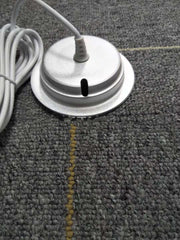 White cylindrical object with a cord on a textured gray surface